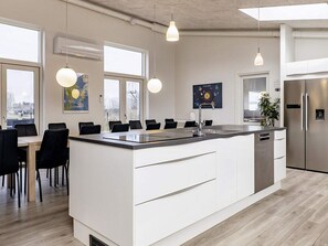 A modern kitchen with a central island, white cabinetry, and pendant lighting.