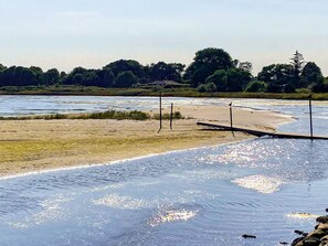 A beach with a wooden walkway, a sandy shore, and a forest in the background. - Holiday Home in Væggerløse (Vaeggerlose)