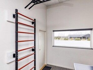 A room with a pull-up bar, a window with a view of buildings, and a door. - Holiday Home in Væggerløse (Vaeggerlose)