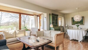 A spacious living room with a sofa, a coffee table, and a dining area with a table and chairs. - 8 Person Holiday Home in Harpelunde (Harpelunde)