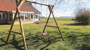 A wooden swing set in a grassy yard with a house in the background. - 8 Person Holiday Home in Harpelunde (Harpelunde)
