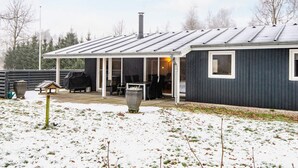 A single-story house with a covered patio area, a chimney, and a small outdoor seating area. - 6 Person Holiday Home in Herning (Herning)