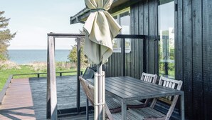 A wooden deck with a table and chairs, overlooking a body of water.