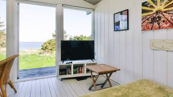 Una habitación con televisor, estantería y vistas al mar.