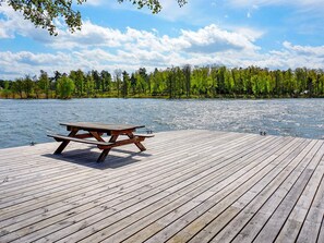 A wooden dock with a picnic table extending over a body of water, surrounded by trees. - 4 Person Holiday Home in Adelso (Adelso)