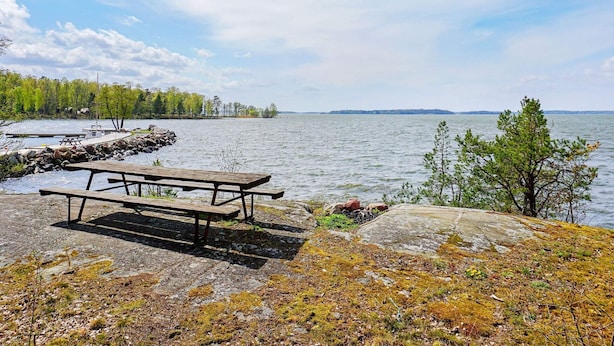 Un espace de pique-nique au bord du lac, avec un banc en bois et une jetée qui s’avance dans l’eau.