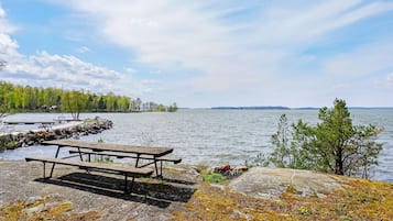 A lakeside picnic area with a wooden bench and a dock extending into the water.