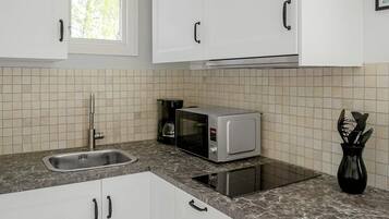 A kitchen with white cabinets, a sink, a microwave, and a coffee maker.