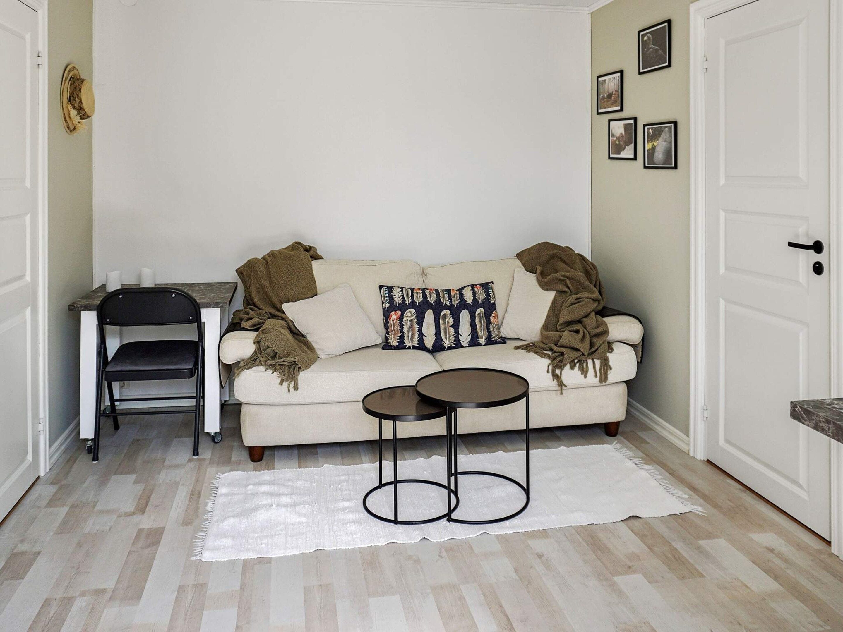 A small, cozy living space with a sofa, two side tables, a chair, and a rug.