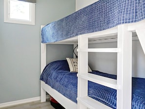 A bunk bed with a blue mattress and white frame, a pillow with text, and a window with a view. - 4 Person Holiday Home in Adelso (Adelso)