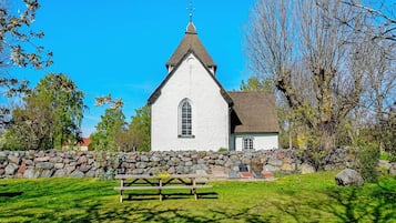 Una iglesia con fachada blanca, un muro de piedra y una mesa de picnic al frente.