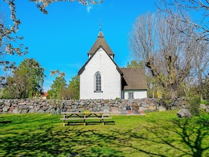 A church with a white facade, a stone wall, and a picnic table in front.