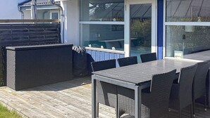 An outdoor patio with a table and chairs, a covered seating area, and a view through a glass door. - Holiday Home in VÃ¦ggerlÃ¸se (Vaeggerlose)