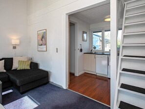 Ett vardagsrum med en mörk soffa, en lampa och en tavla på väggen.