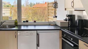 A modern kitchen with a dishwasher, oven, and coffee maker.