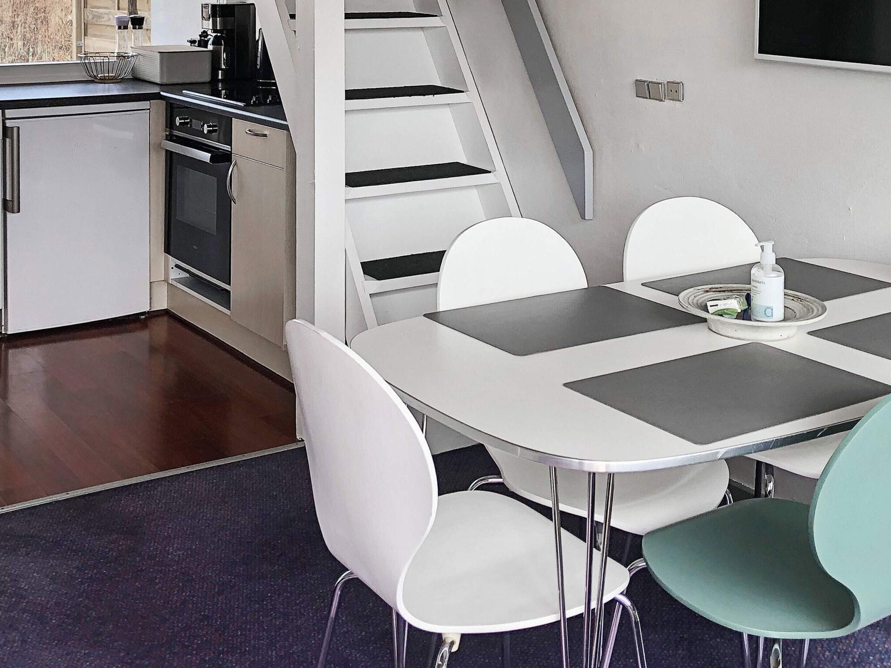 A modern kitchen with a dining area, including a table with chairs, a coffee machine, and a microwave.