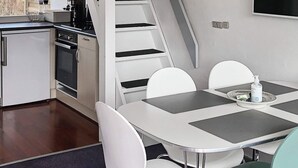 A modern kitchen with a dining area, including a table with chairs, a coffee machine, and a microwave. - Holiday Home in VÃ¦ggerlÃ¸se (Vaeggerlose)