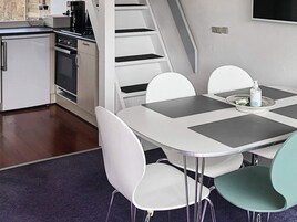 Et moderne køkken med spiseplads, inklusive et bord med stole, kaffemaskine og mikroovn.