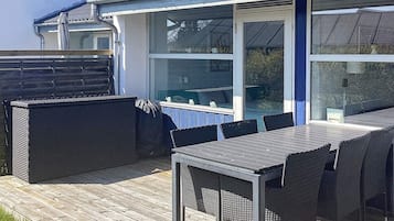 An outdoor patio with a table and chairs, a covered seating area, and a window overlooking a garden.