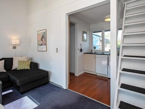 Ein kompakter Wohnbereich mit einer Couch, einer Küchenzeile und einer Treppe.