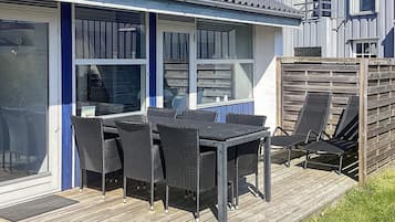A deck with a table and chairs, a sliding glass door, and a wooden fence.