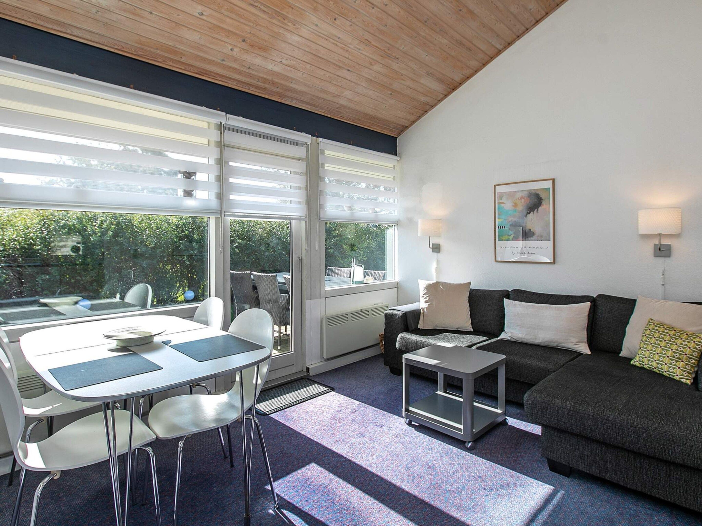A modern living room with a dining area, a sofa, a coffee table, and a small cart.