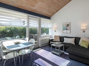 A modern living room with a dining area, a sofa, a coffee table, and a small cart. - Holiday Home in VÃ¦ggerlÃ¸se (Vaeggerlose)