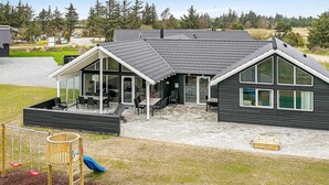 A modern house with a patio, a trampoline, and a play area. - Holiday Home in Blåvand (Blavand)