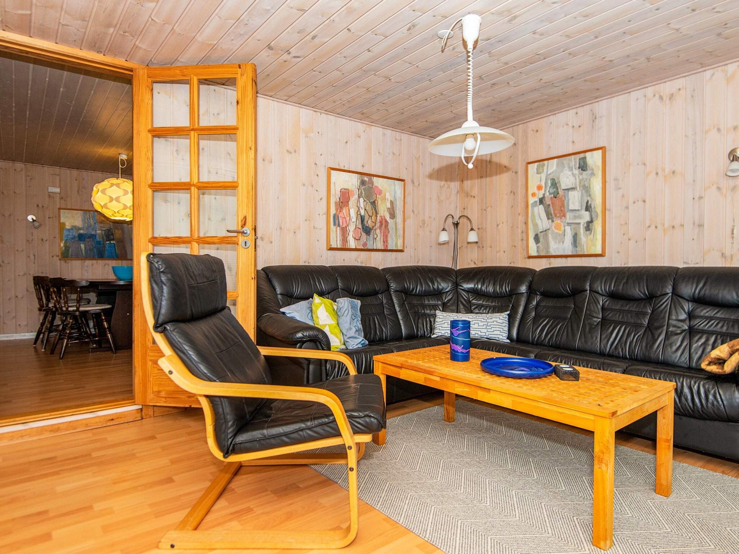 Una sala de estar amoblada con un sofá, una mesa de centro de madera, un sillón de cuero y un comedor con sillas y una mesa.