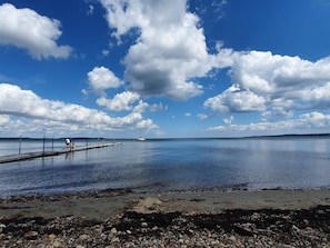 Un lago tranquilo con un muelle que se adentra en el agua, rodeado por una costa rocosa.