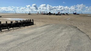 Une plage avec une zone de sable et un chemin pavé.