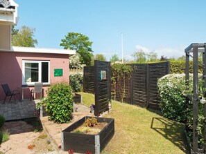A residential backyard with a patio area, a wooden fence, and a garden bed.