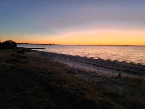 A beach with a calm sea and a sunset.