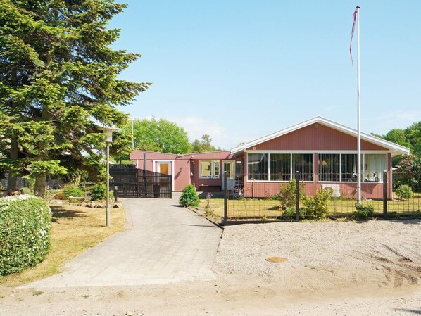 A single-story building with a red exterior and a white roof, featuring a large window and a flagpole.