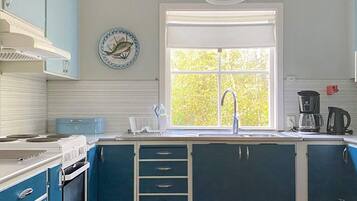 A kitchen with a window, a sink, a stove, and cabinets.