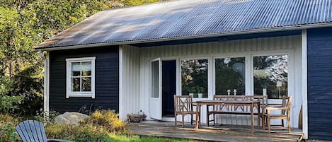 A single-story house with a porch, a dining table, and chairs.