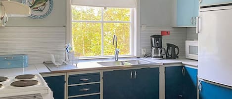 A kitchen with a window, a sink, a stove, and cabinets.