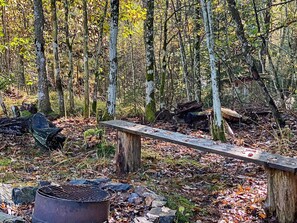 A forest with a metal grill and a wooden bench. - 4 Person Holiday Home in Skanes-fagerhult (Skånes Fagerhult)