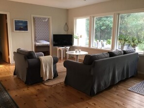 Una sala de estar acogedora con sofá, televisor, una mesita y ventana con vistas a zonas verdes.
