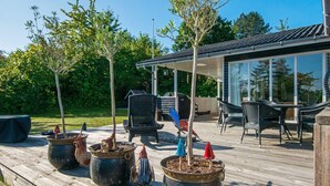 A wooden deck with potted plants and outdoor furniture. - Holiday Home in Ebeltoft (Ebeltoft)