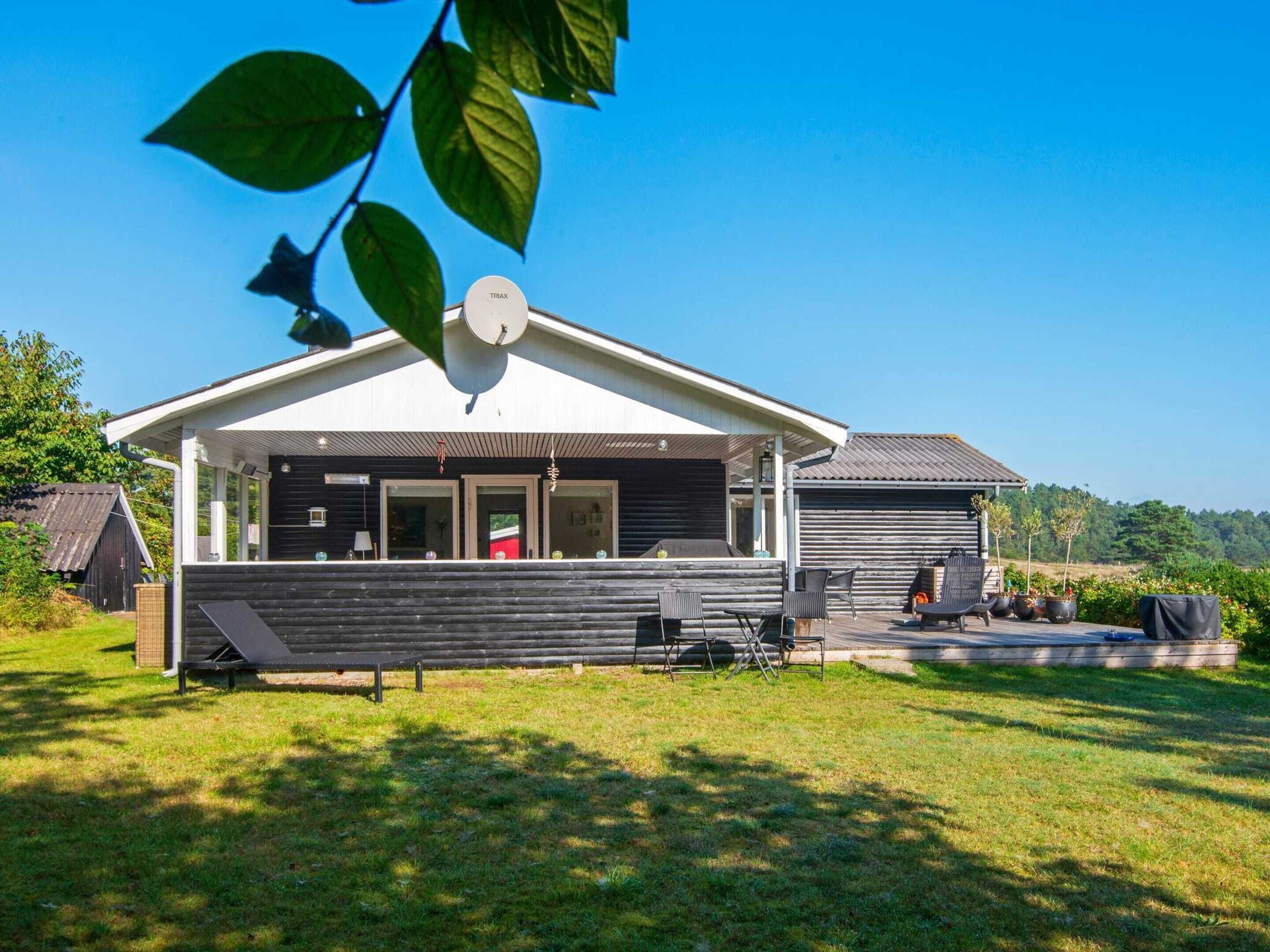 A modern house with a covered porch, a barbecue area, and outdoor seating.