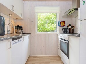 A compact kitchen with a window, a coffee maker, a kettle, and a microwave. - Holiday Home in Ebeltoft (Ebeltoft)