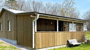 Ein Holzhaus mit überdachter Veranda, einer Bank und einem kleinen Außenbereich.