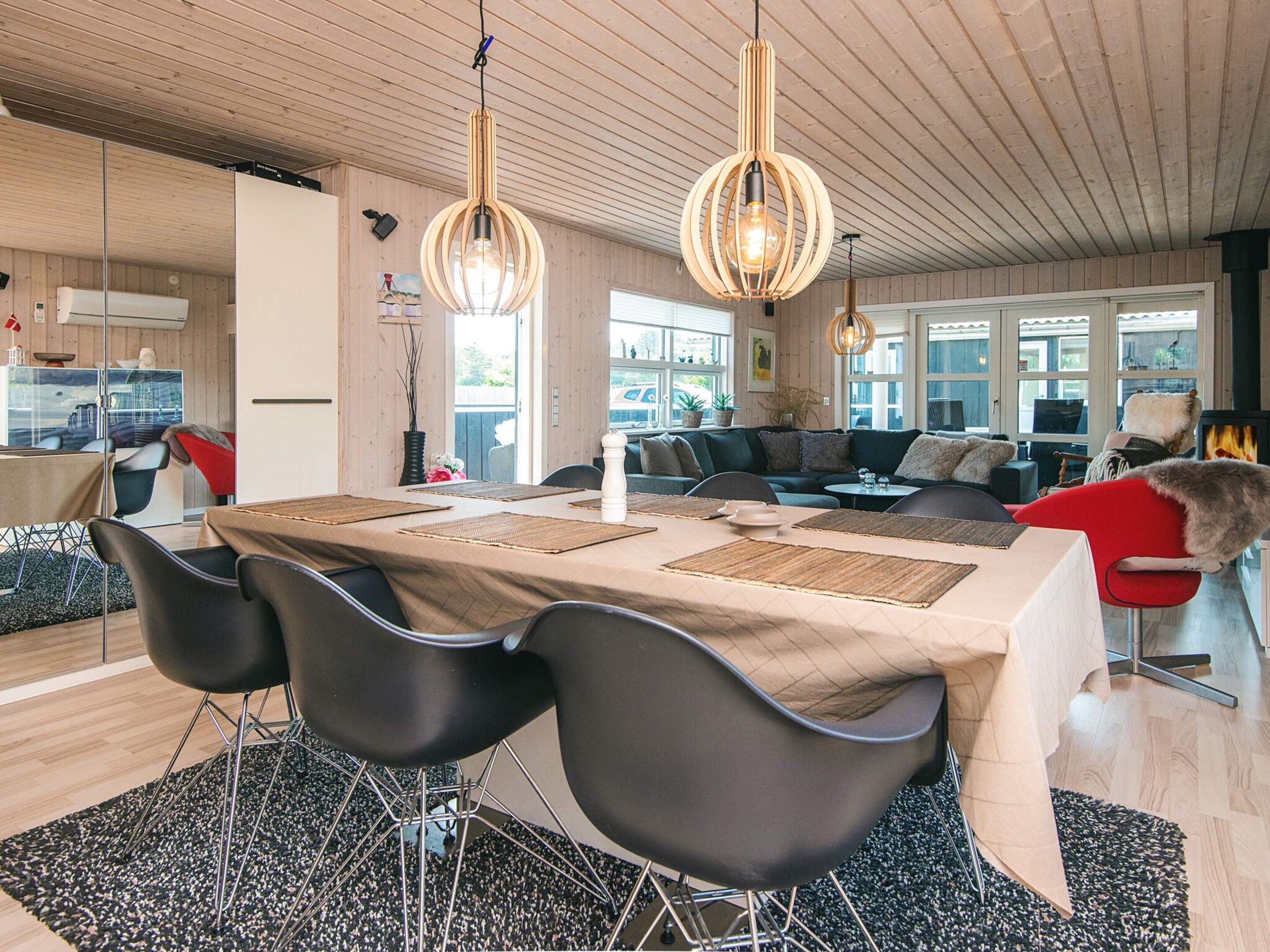 A modern dining area with a wooden table, black chairs, and two hanging pendant lights.