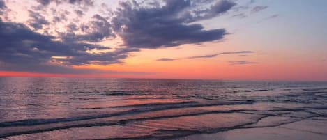 Una playa con olas y un atardecer.