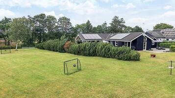 A residential area with a well-maintained lawn, a soccer goal, and a row of houses with solar panels.