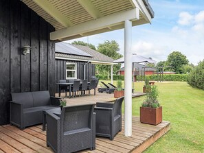 A covered patio area with outdoor furniture, a grill, and a view of a house in the background. - Holiday Home in Hadsund (Hadsund)