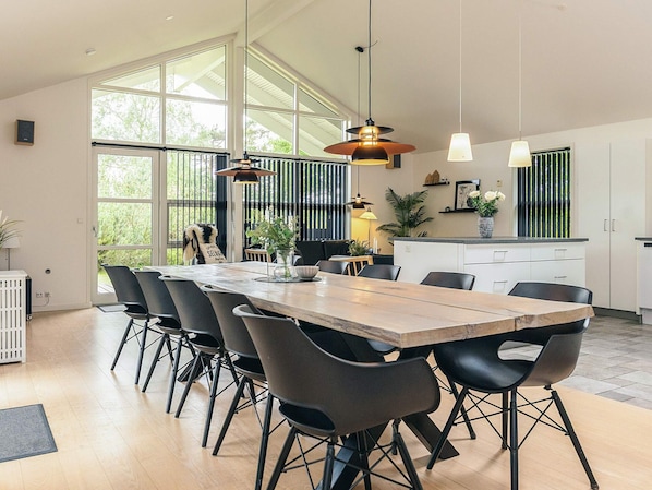 Una cocina moderna con una amplia mesa de comedor, sillas negras e iluminación colgante.