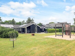 A residential property with a large backyard, a barbecue area, and a wooden play structure. - Holiday Home in Hadsund (Hadsund)
