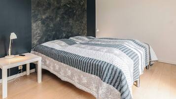 A bedroom with a bed, a bedside table, and a lamp.